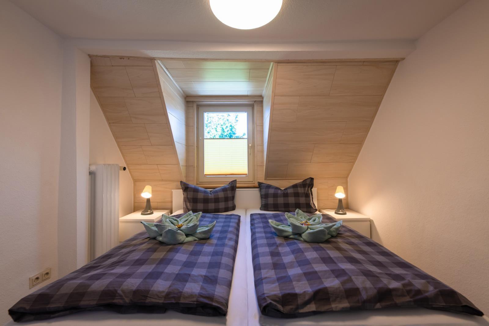 Zimmer mit Doppelbett, Holzdecke und Fenster mit Blick nach draußen.