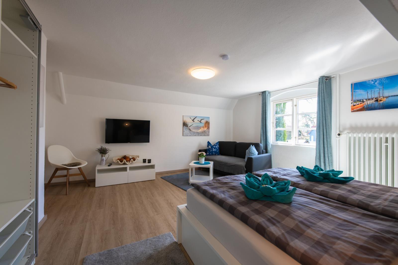 Zimmer mit Doppelbett, Sofa, Fernseher und Fenster mit Blick.