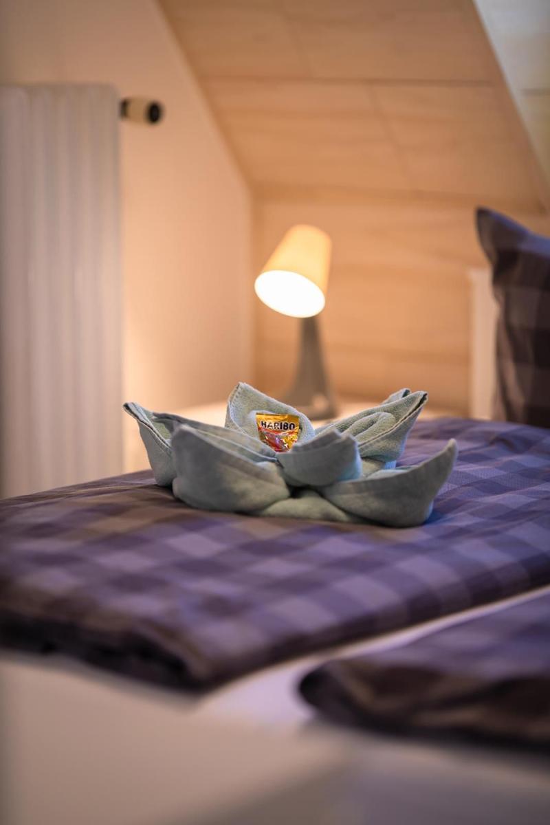 Ein Bett mit kariertem Bettlaken und einem Handtuch, das wie eine Blume gefaltet ist.