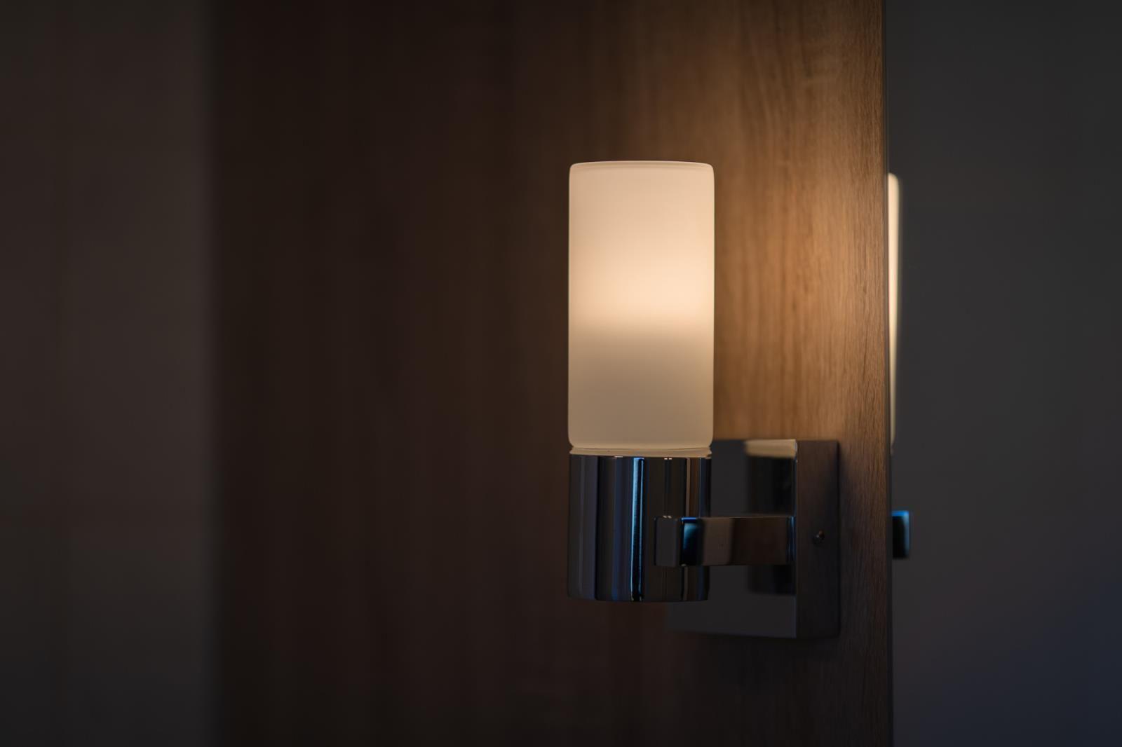 Eine Wandlampe mit glasfaserbeleuchteter Schirm an einer Holzwand.