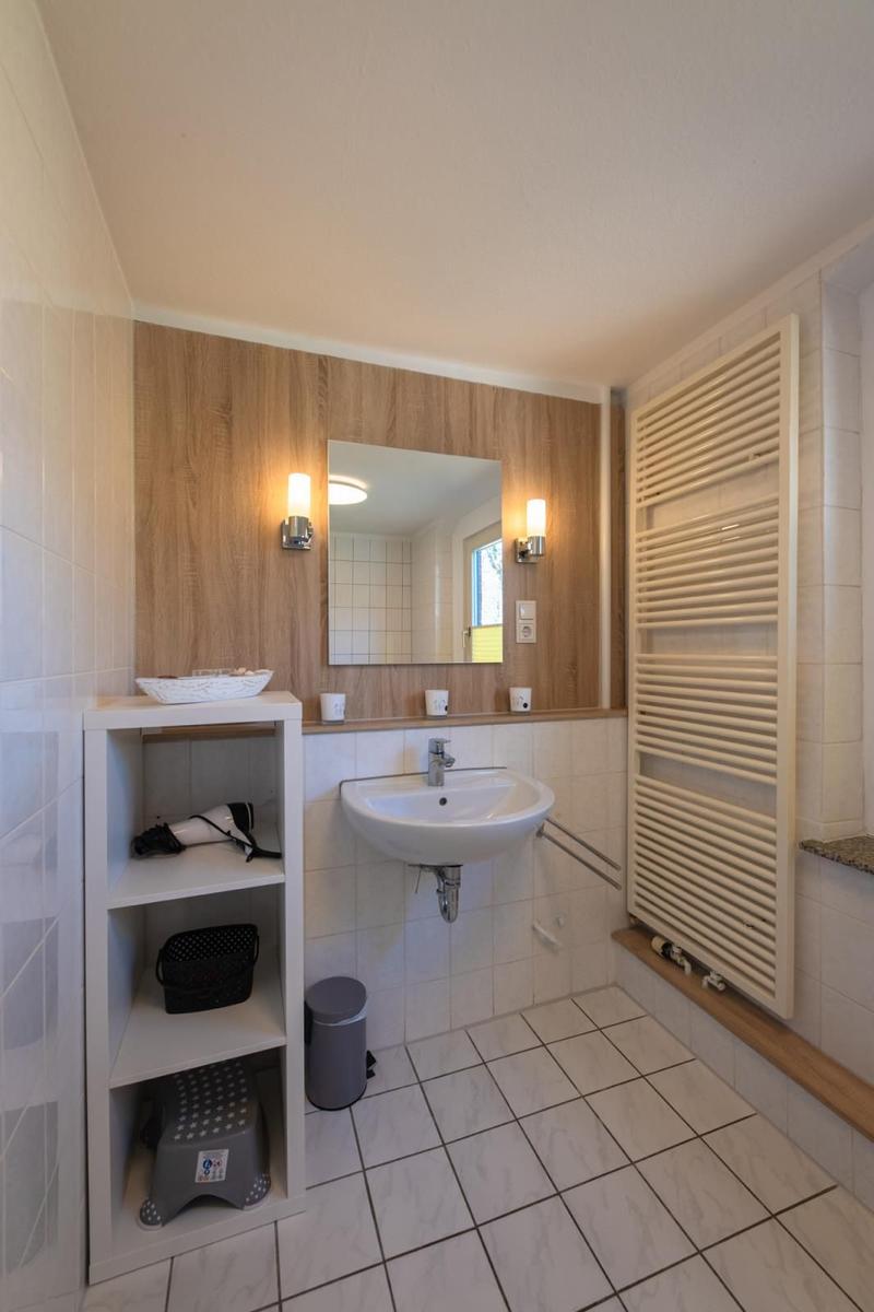 Badezimmer mit Waschbecken, Spiegel, Heizkörper und Regal