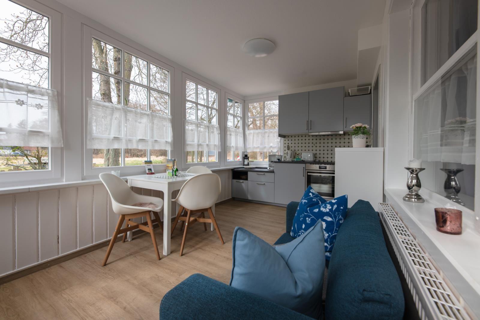 Living kitchen with dining area, sofa, and windows to the outside.