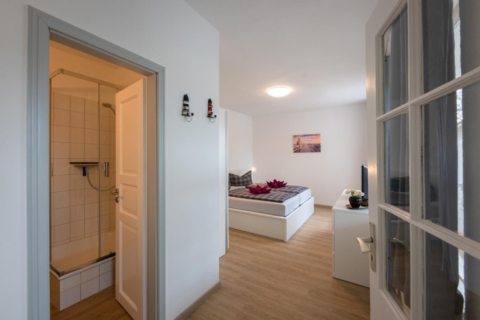 Bedroom with shower and window. Bed with pillows and flowers.