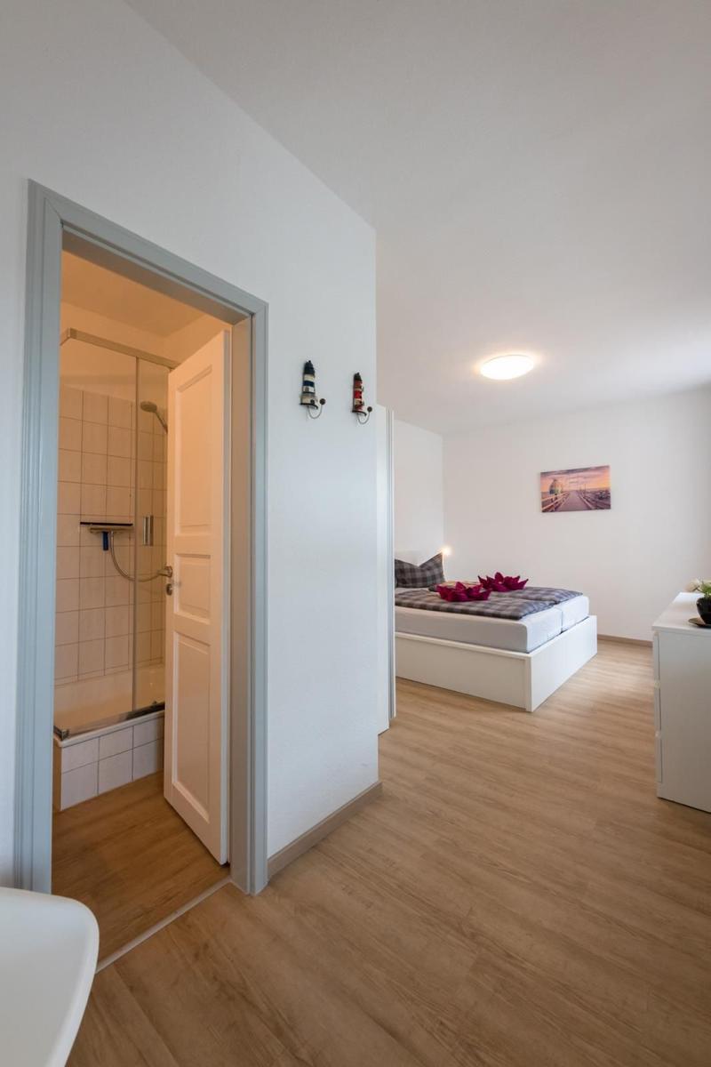 Bedroom with shower and bed with red flowers.