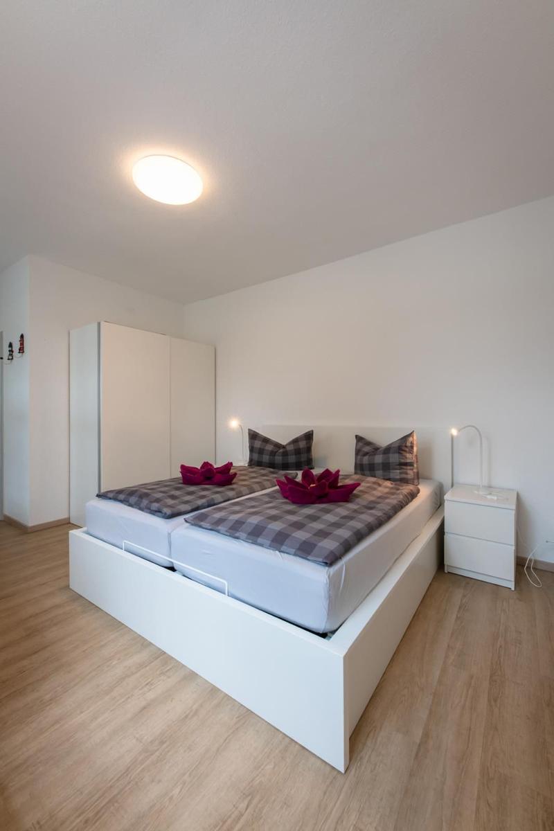 Bedroom with double bed, nightstand, and wardrobe. Wooden floor and white walls.