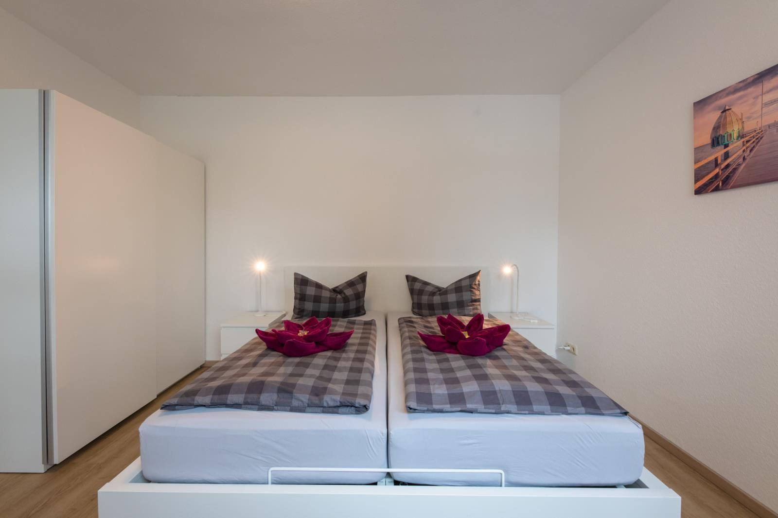 Room with two beds, nightstands, and wall art. Bed with pillows and bedding.
