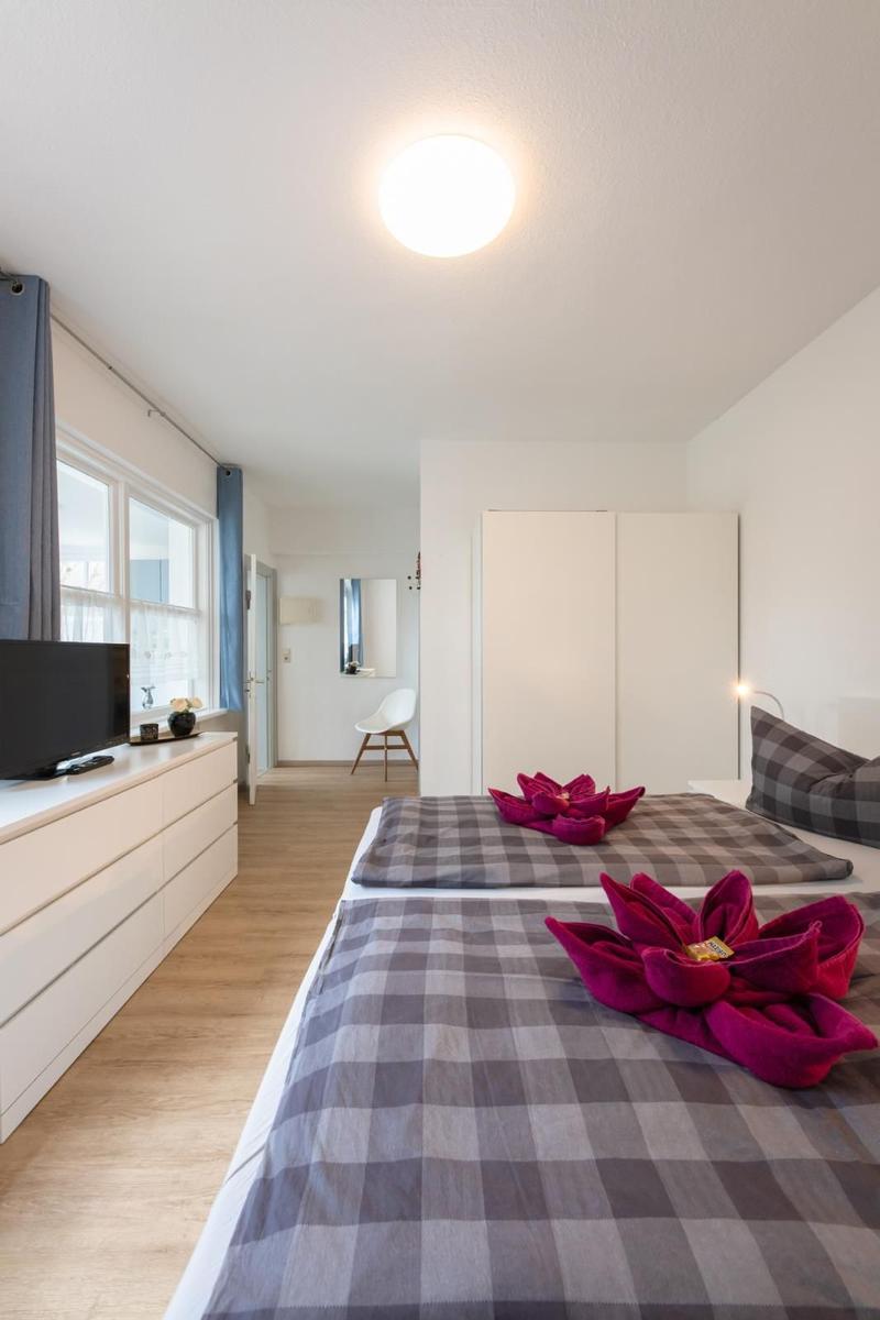 Bedroom with two beds, window, wardrobe, and TV.
