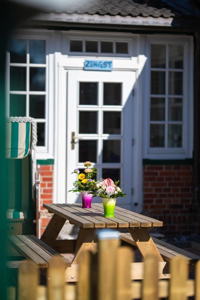 Wooden table with flowers in front of a white door with sign ZINGST