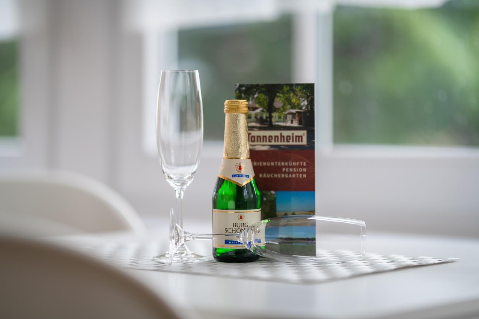 On the table, a bottle and two glasses sit next to a brochure.