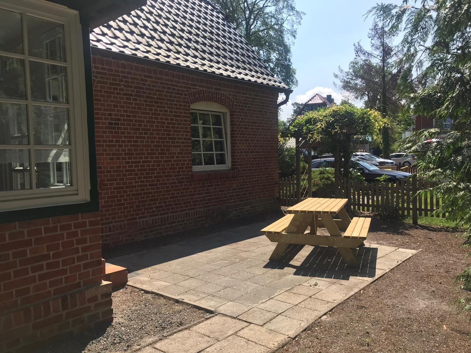 Red brick building with wooden table on paved yard