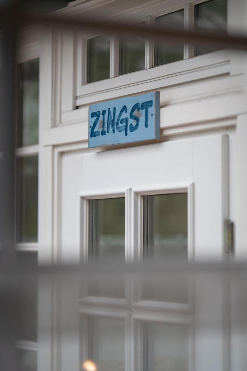 A blue sign with the text ZINGST on a white building facade.