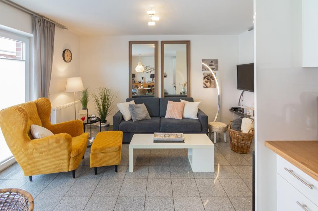 Living room with gray sofa, yellow armchair, and white furniture.