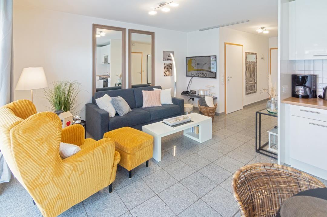 Living room with sofa, yellow chairs, and kitchen area.