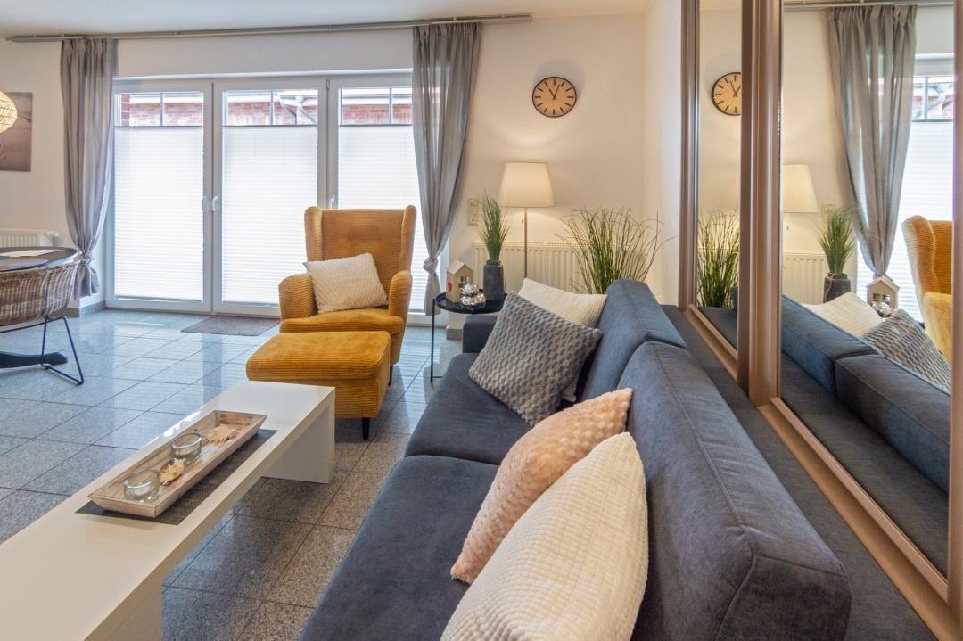 Living room with gray sofa, yellow armchair, and mirrored wall.