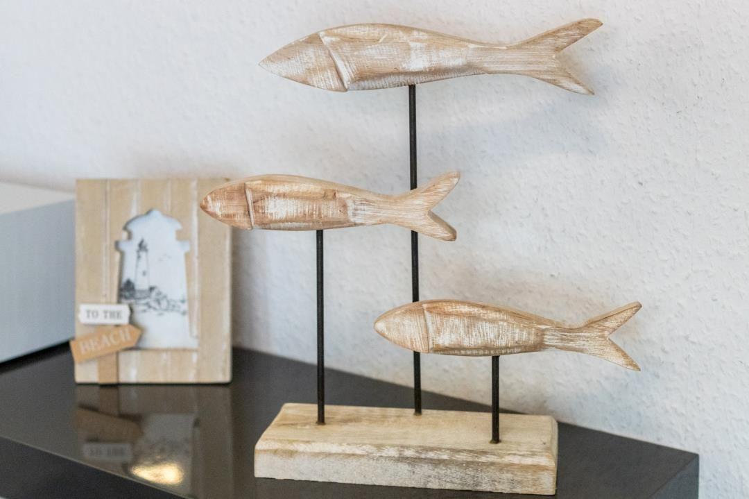 Three wooden fish on stands, next to a lighthouse picture.