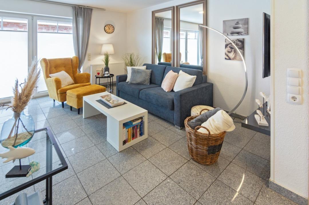 Living room with sofa, armchair, coffee table, and wall mirror.