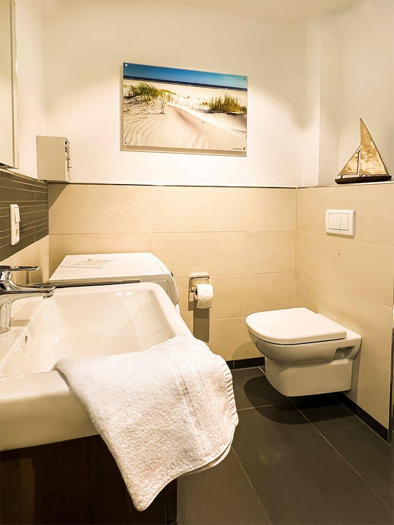Bathroom with sink, toilet, and wall picture with beach motif.