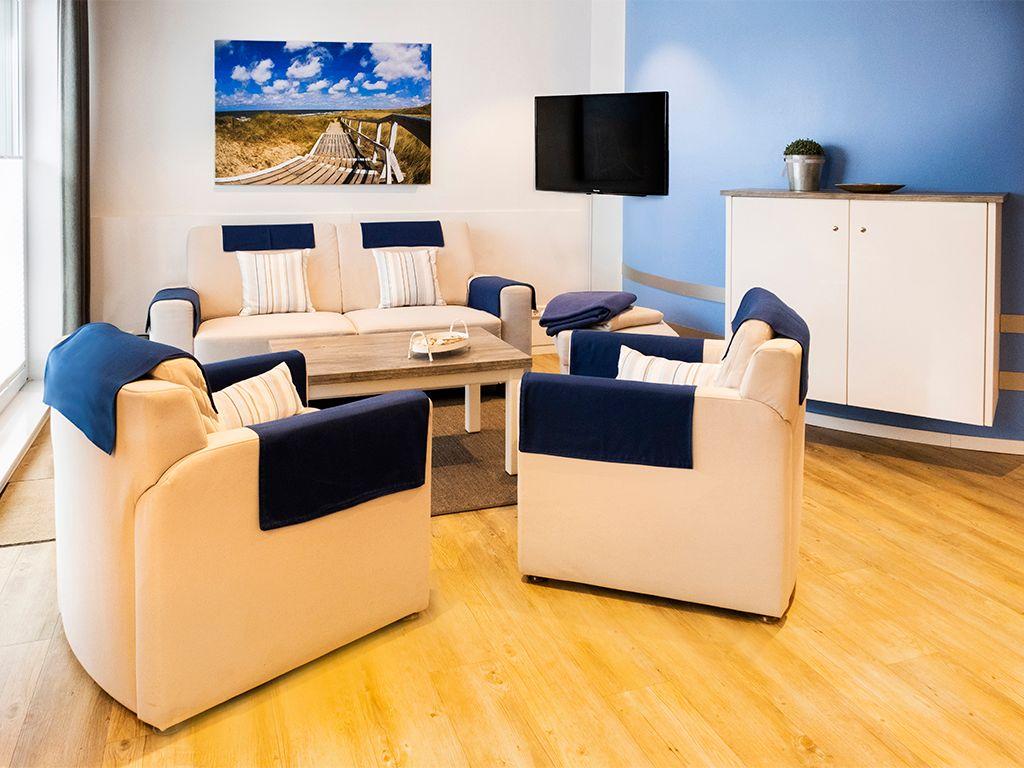Living room with sofa, two armchairs, TV, and wall art.