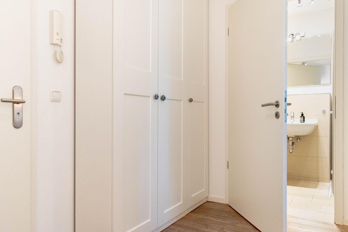 Flur mit Schrank und Tür zum Bad mit Waschbecken