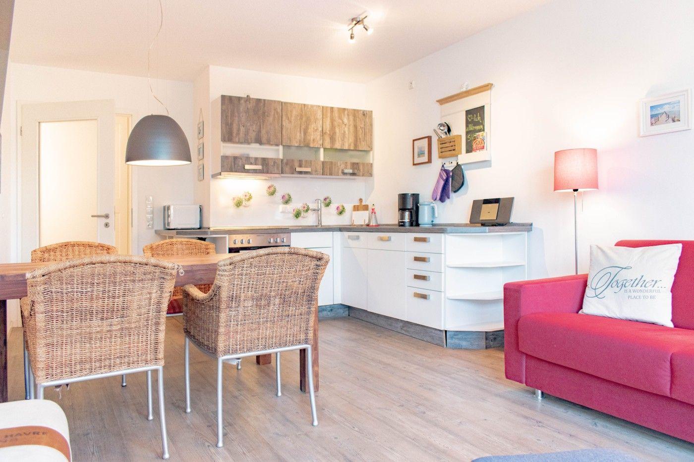 Küche mit Essbereich und rotem Sofa. Holzfußboden und weiße Wände.