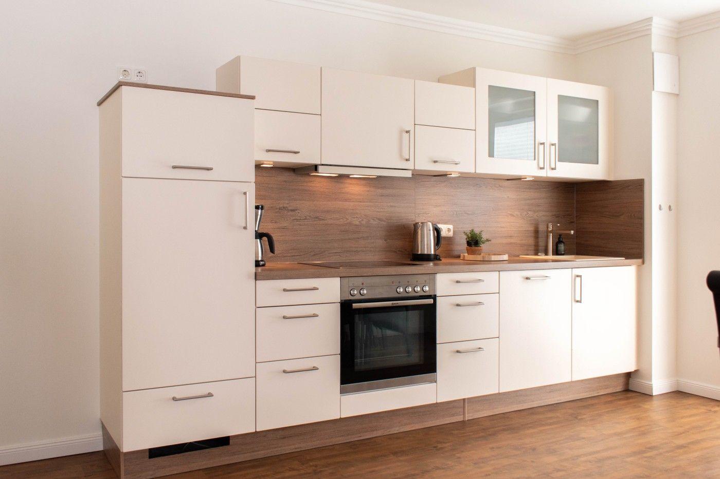 Moderne Küche mit weißen Schränken, Holzoptik und integriertem Ofen.