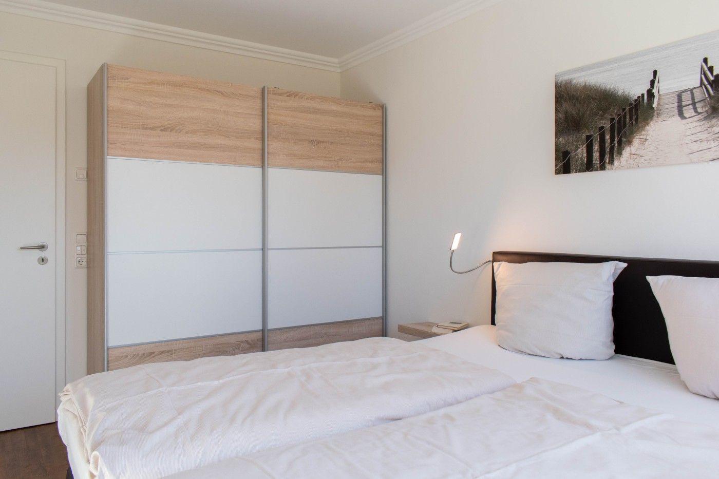 Schlafzimmer mit Doppelbett, Kleiderschrank und Wandbild.