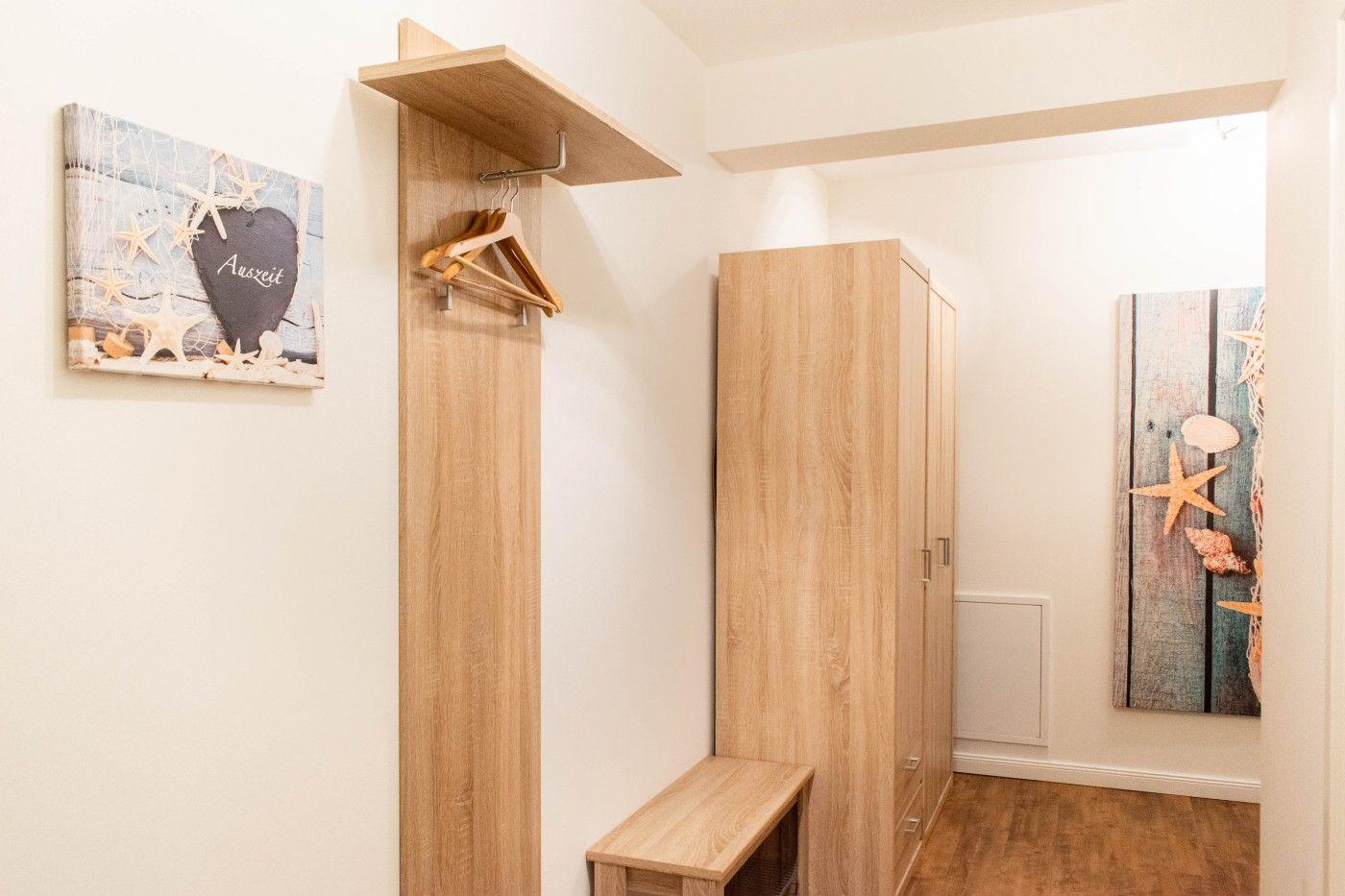 Schlafzimmer mit Kleiderständer, Kleiderschrank und Wandbild mit Meeresmotiv.
