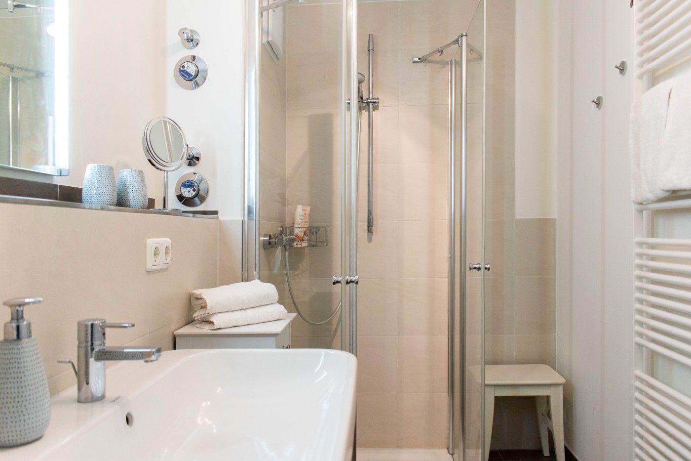 Badezimmer mit Dusche, Waschbecken und Handtuchheizkörper