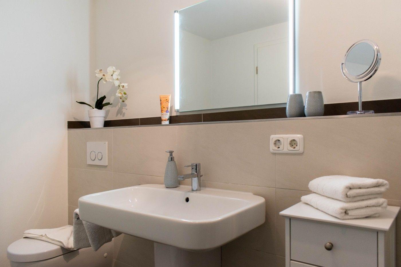 Badezimmer mit Waschbecken, Spiegel, Toilette und Handtuchständer.