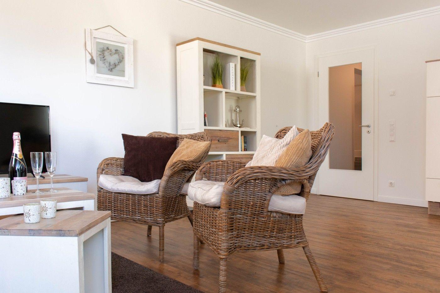 Wohnzimmer mit zwei Rattan-Stühlen, Holzboden und weißen Wänden.