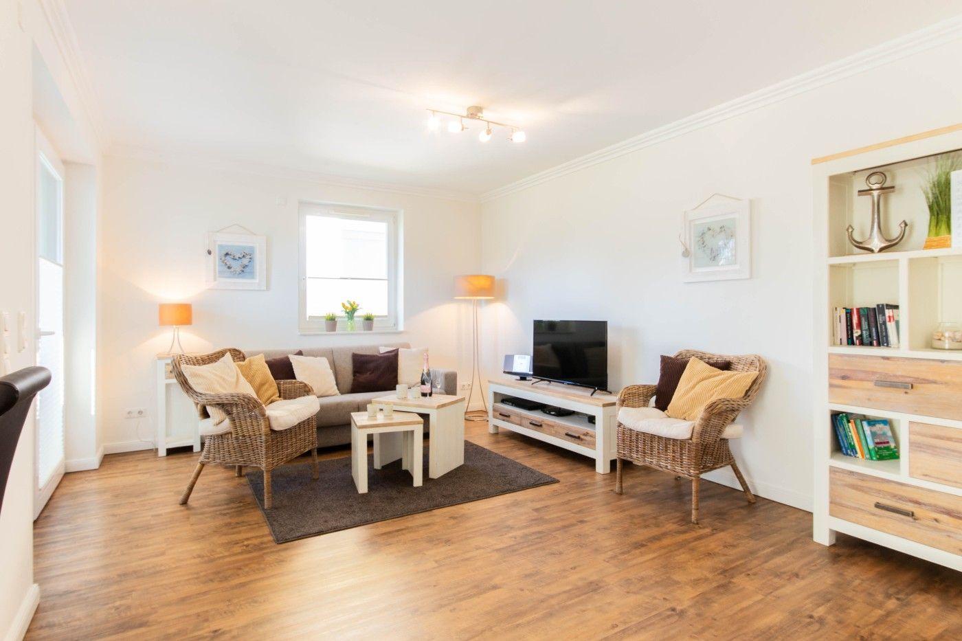 Wohnzimmer mit Sofa, zwei Stühlen, Fernseher und Holzboden.