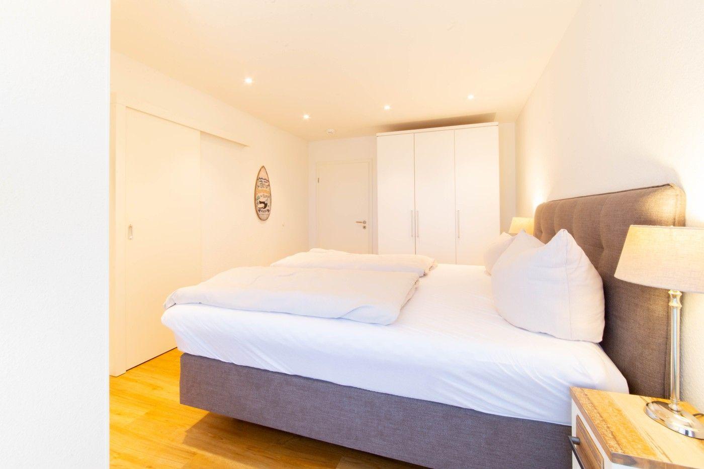 Schlafzimmer mit Bett, Nachttisch und Kleiderschrank.