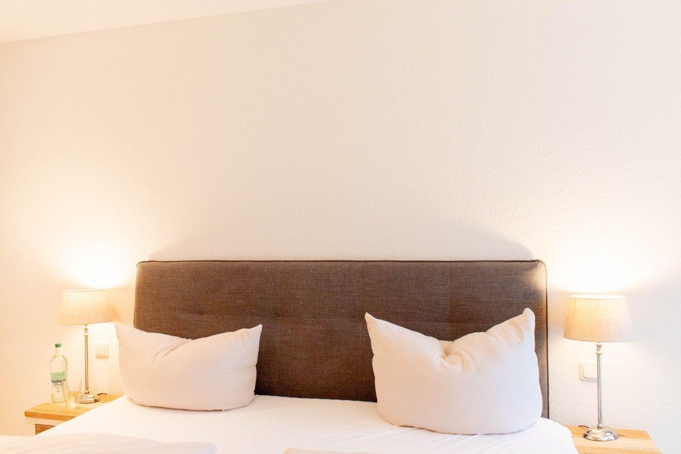 Ein Bett mit zwei Kissen, einem Kopfteil und zwei Nachttischen mit Lampen.