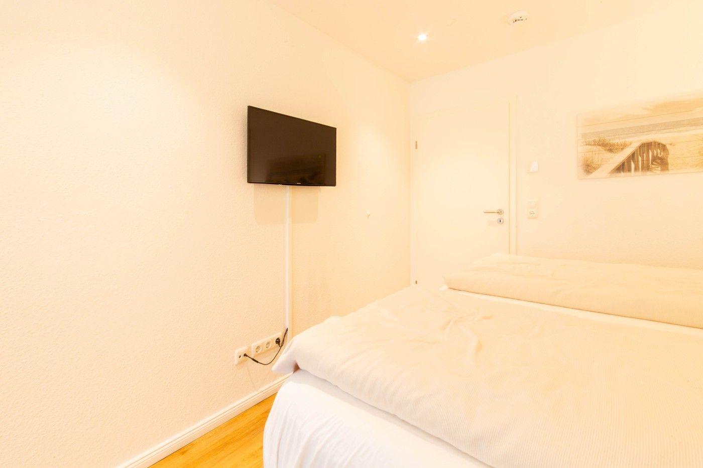 Schlafzimmer mit Bett, Wandbild und Flachbildschirm-TV an der Wand.