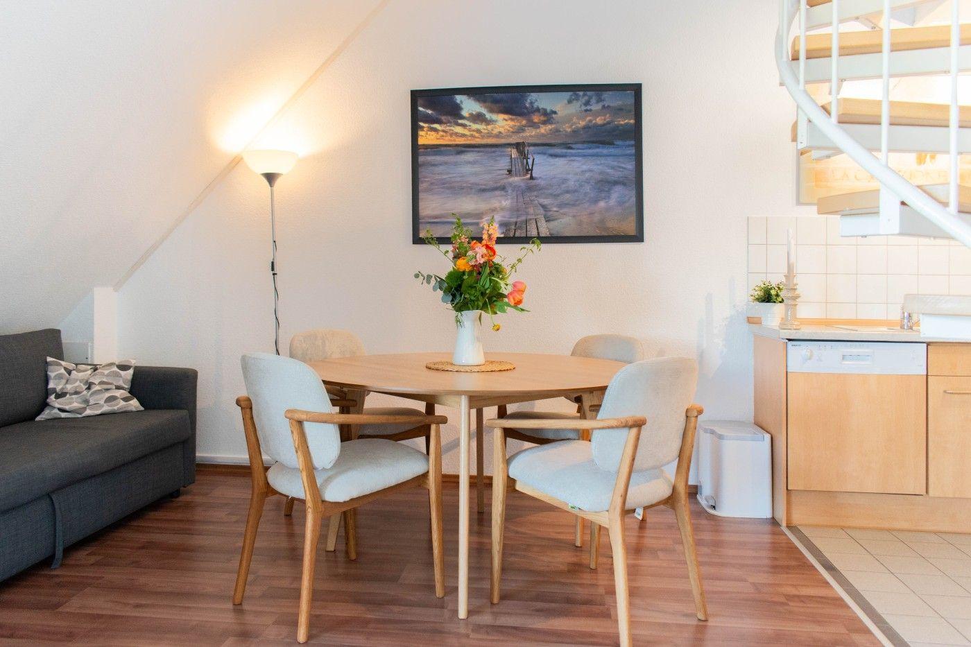 Essbereich mit Tisch, Stühlen und Sofa. Wandbild und Wendeltreppe sind sichtbar.