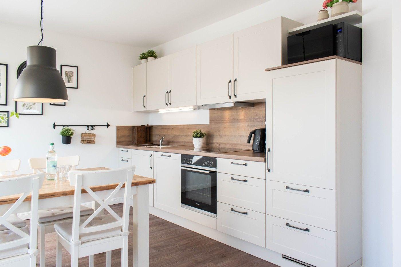 Küche mit weißen Schränken, Holzoberfläche und integriertem Backofen.