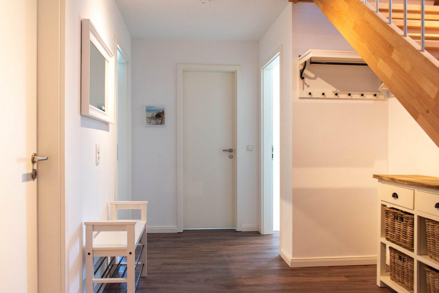 Eingangsbereich mit Holzboden, Kleiderständer und Stufen zur Treppe.