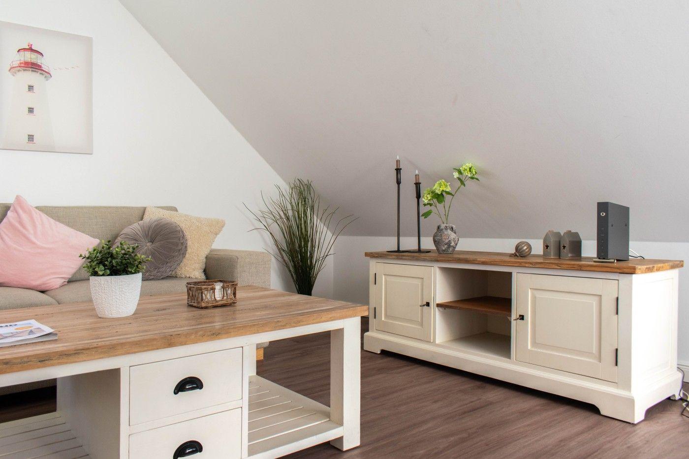 Wohnzimmer mit Sofa, Tisch und Sideboard unter schräger Decke.