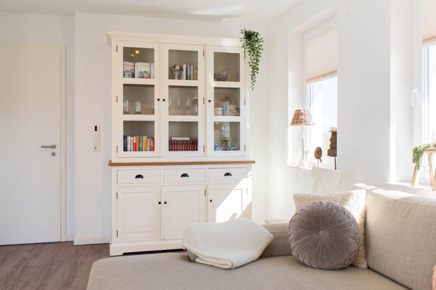 Ein Wohnzimmer mit einem weißen Sideboard, einem Sofa und einem Fenster.