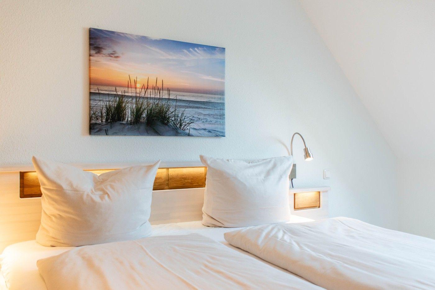 Schlafzimmer mit Bett, Wandbild und Stehlampe.