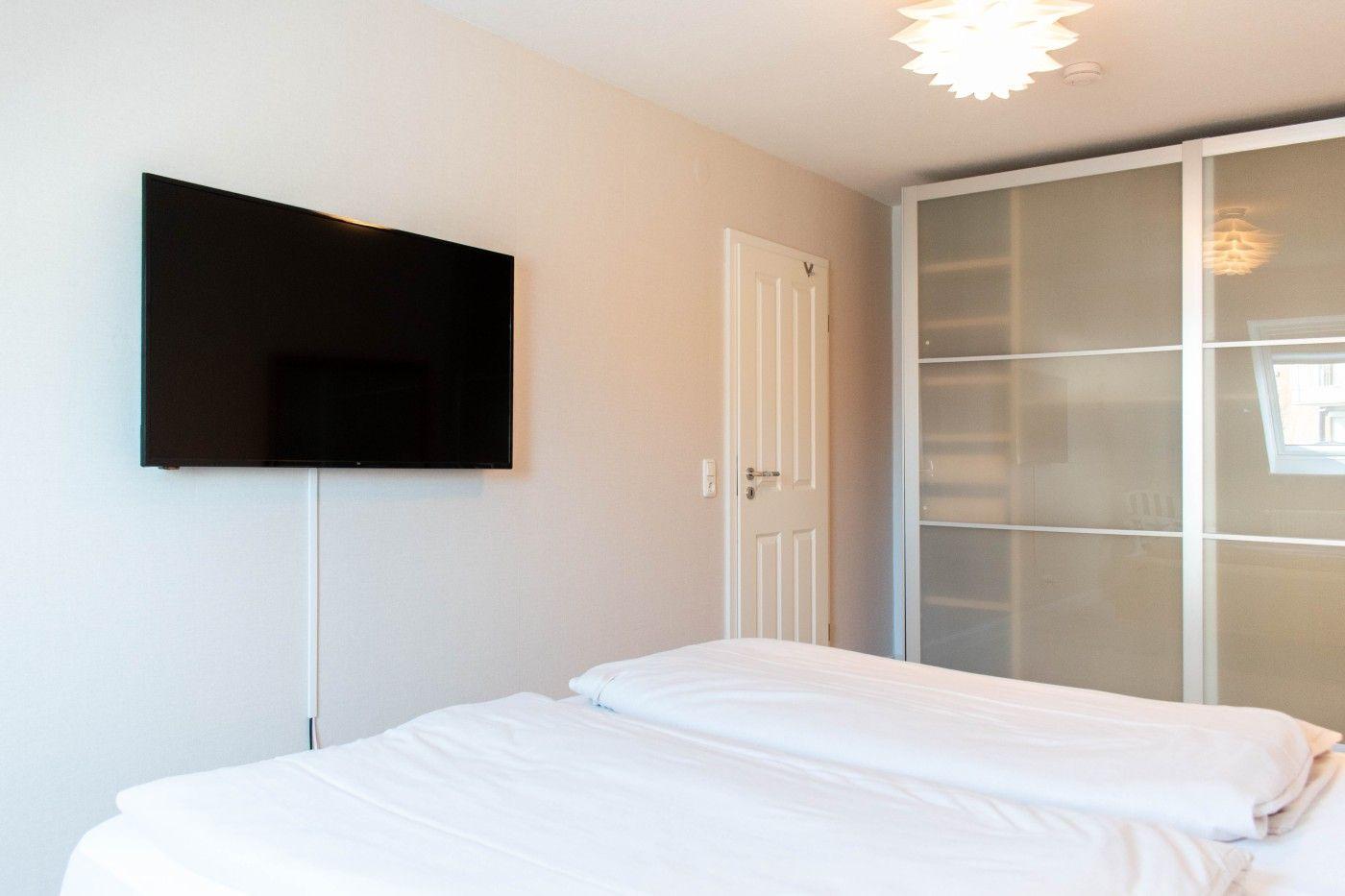 Schlafzimmer mit Bett, Fernseher und Schrank.