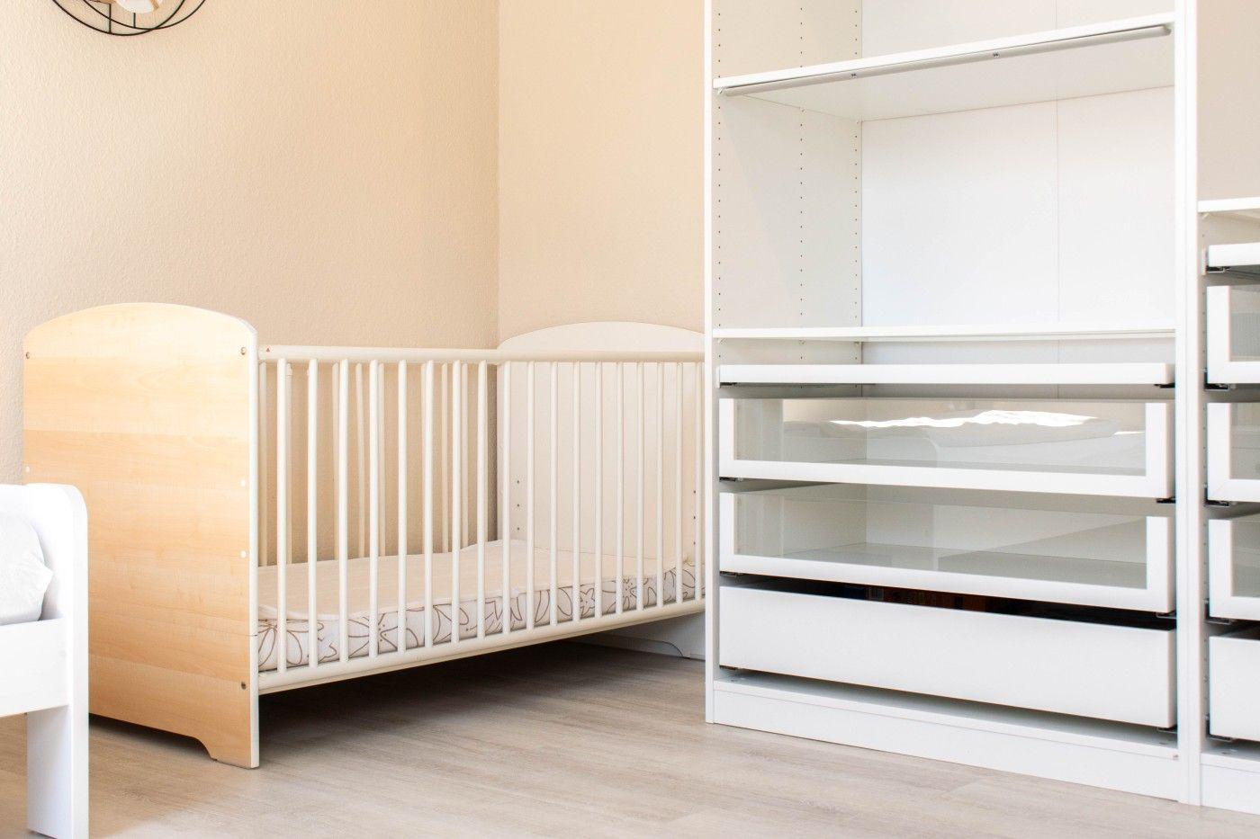 Kinderzimmer mit Babybett und weißen Schränken