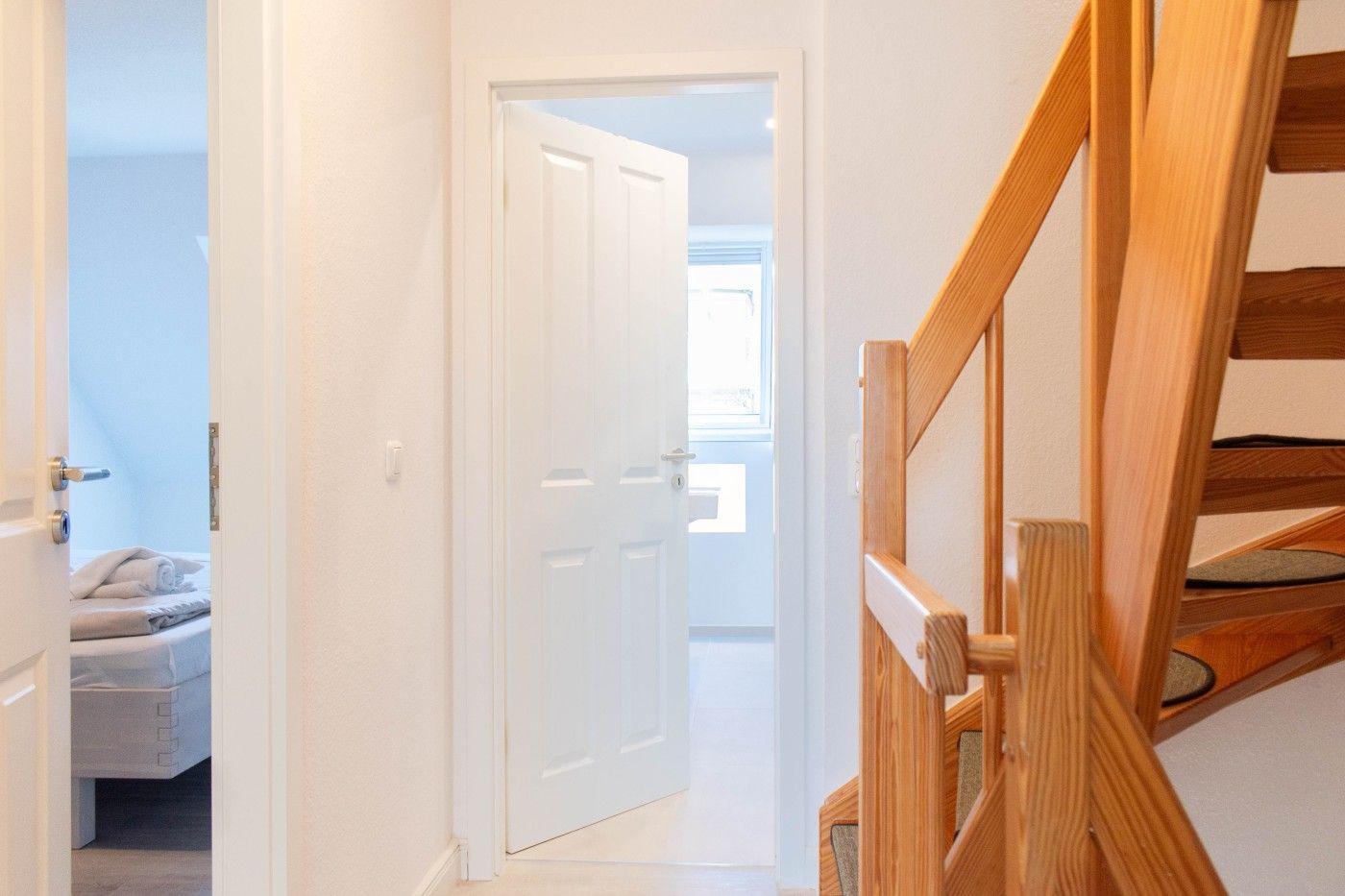Haus mit Holztreppe, Schlafzimmer und Bad. Treppe führt zur oberen Etage.