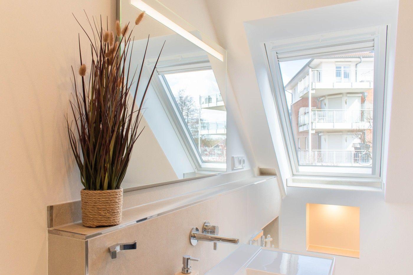 Badezimmer mit Dachfenster, Spiegel und Pflanze auf Waschbecken.