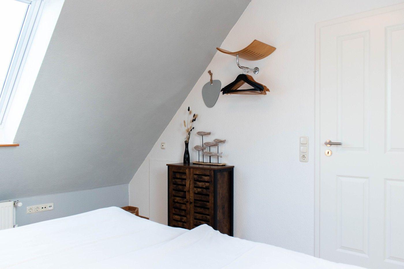 Schlafzimmer mit Dachschräge, weißer Tür und dunklem Schrank.