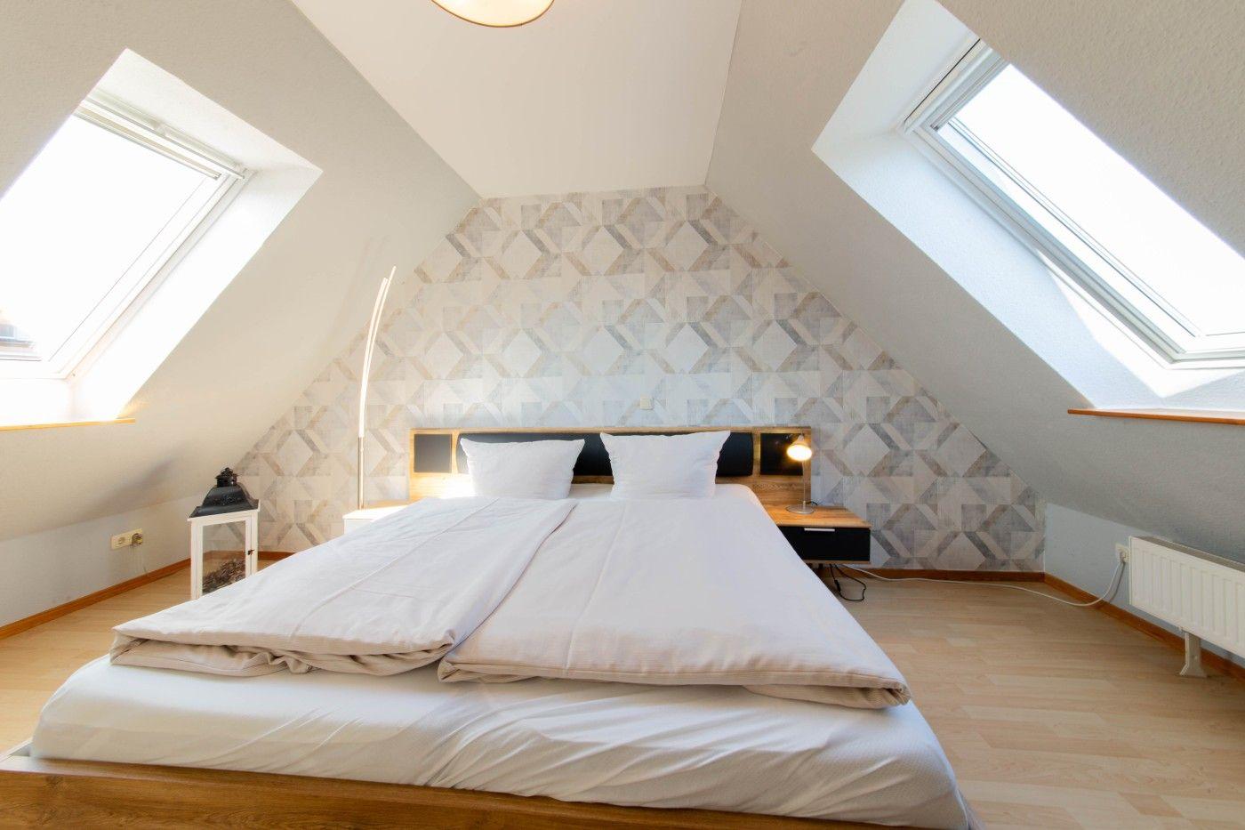 Schlafzimmer mit Dachfenstern, Bett und gemusterter Wand
