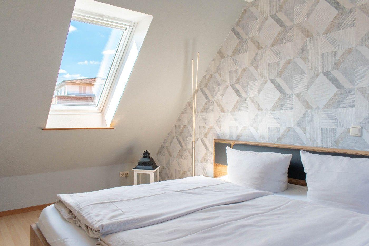 Schlafzimmer mit Dachschrägen, Dachfenster und gemusterter Wand.