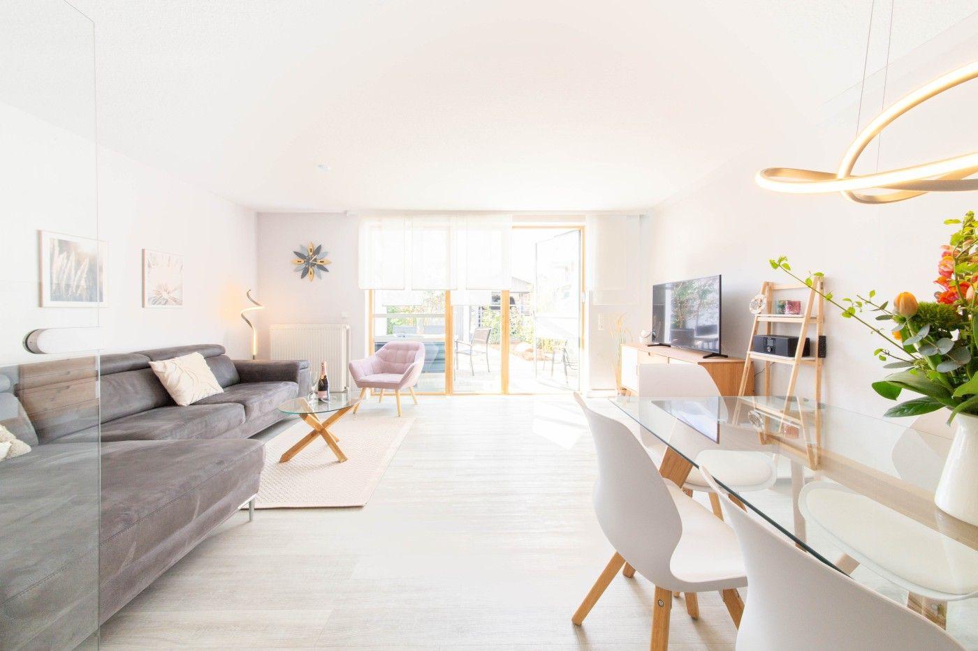 Wohn- und Essbereich mit Sofa, Esstisch und TV. Terrasse mit Gartenansicht.