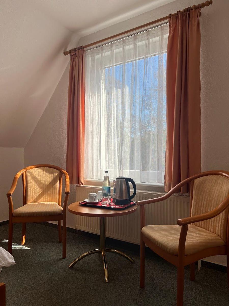 Zwei Stühle und ein Tisch vor einem Fenster mit Vorhängen.