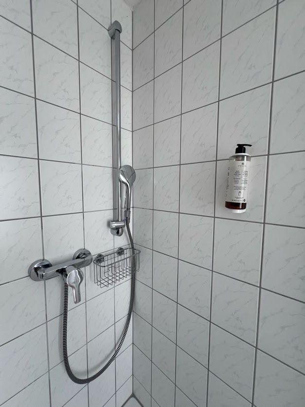 Dusche mit Duschbrause und Seifenspender an Wand